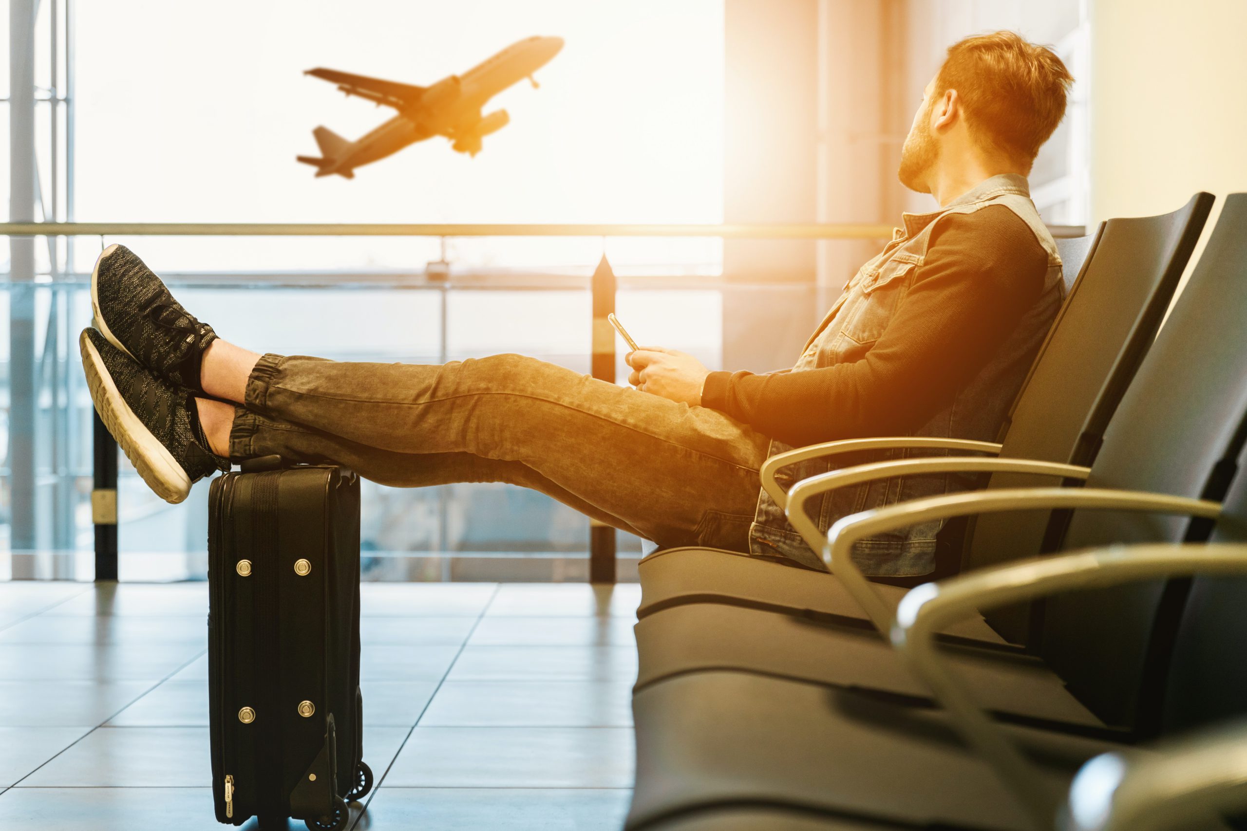 Man waiting at the airport watches a plane take off