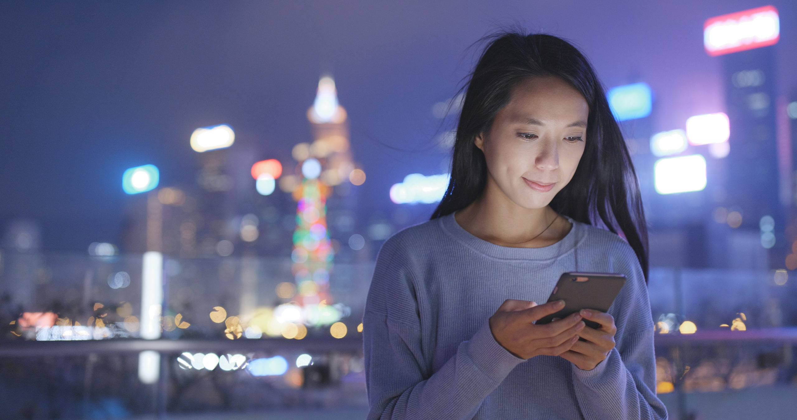 Asian Woman look at smart phone in city at night