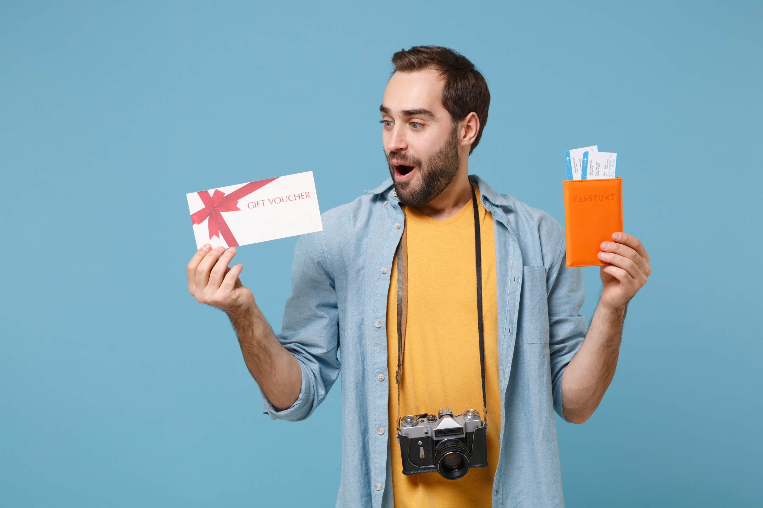 Happy traveler is holding a gift card and passport