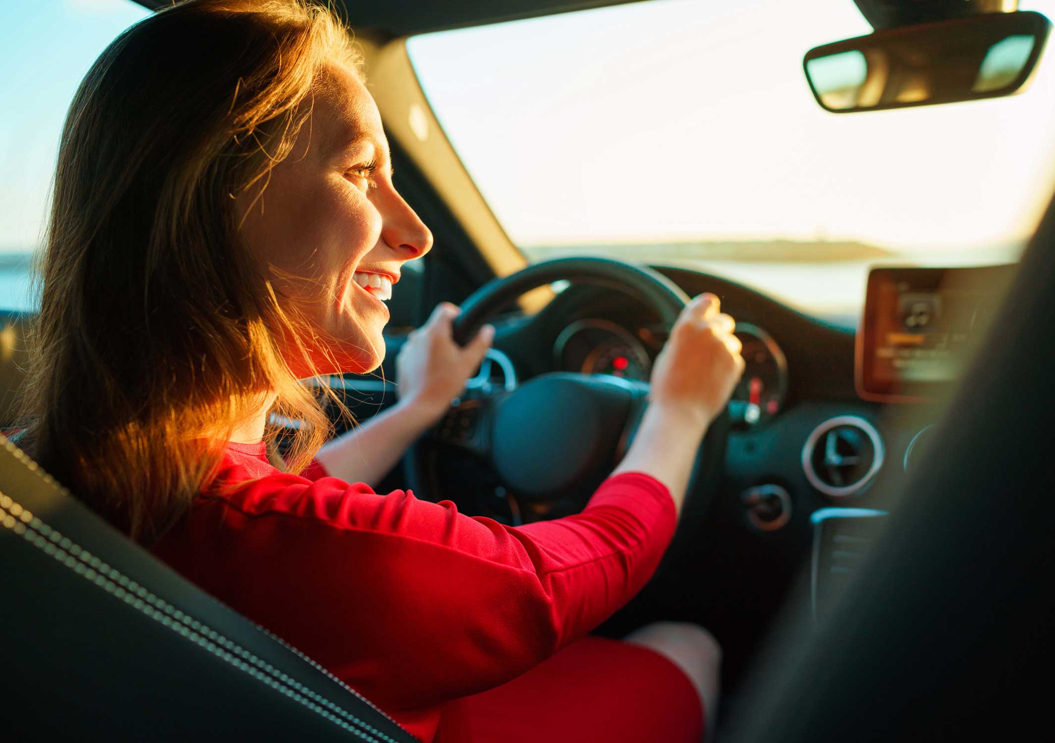 Woman driving the car and smiling at the passenger next to her