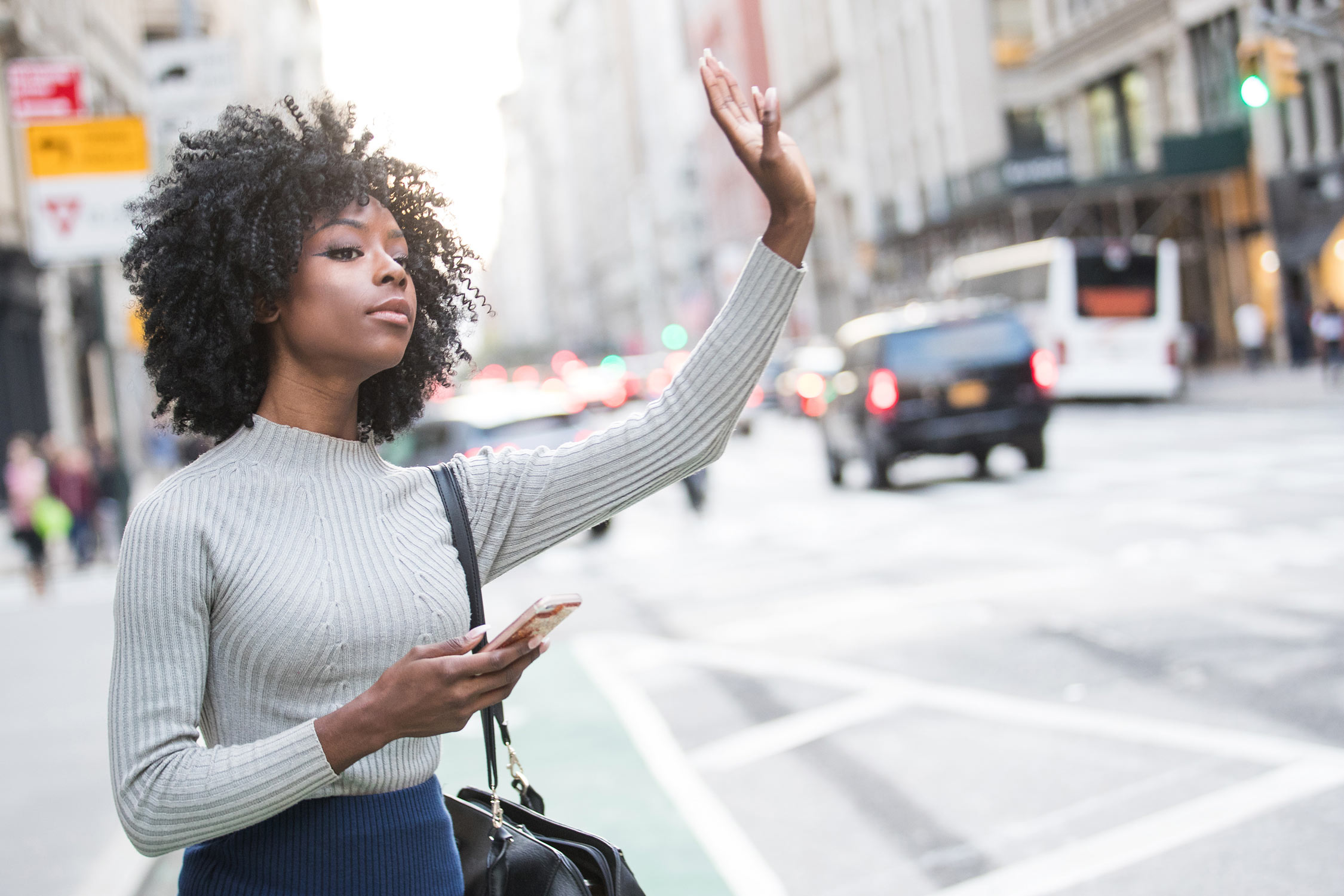 Woman hailing ride share car service in a city street