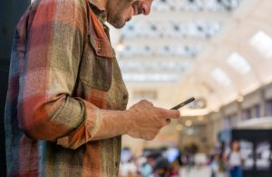 Happy traveler use his phone in an airport