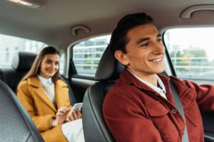 Driver and woman with smartphone in a private transfer car